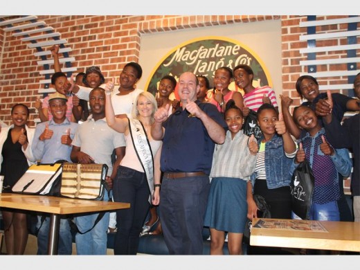 Mrs Africa finalist Wilma Ryan, and Quinton Cronje, owner of John Dory's, with the 14 matric learners from the Phumelela Outreach Programme.