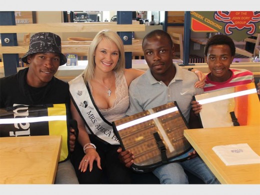 Some of the learners from the Phumelela Outreach Programme hold the desk bags donated to them by Mrs Africa finalist Wilma Ryan (second in the picture). The learners are Lucky Mokoena (left), Kwenzo Conjwa and Mike Hlophe.