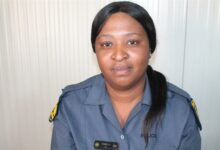 Policewoman in uniform sitting against a white background.