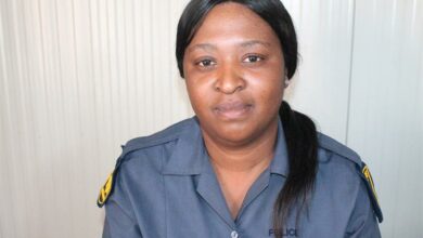 Policewoman in uniform sitting against a white background.
