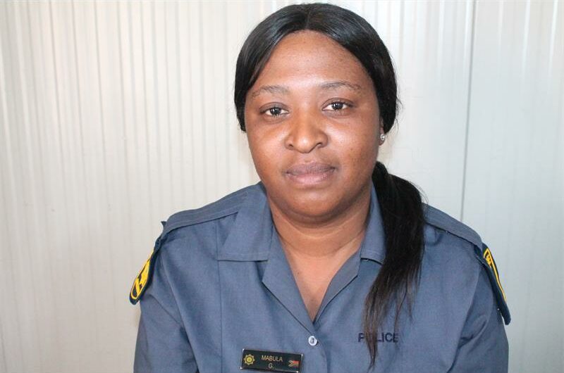 Policewoman in uniform sitting against a white background.
