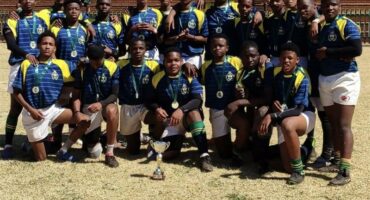 Young rugby team celebrating victory with medals and trophy, showing team spirit and sports achievement.