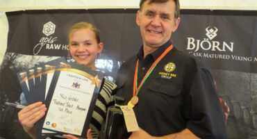 Two people pose with certificates and a bottled product in front of a banner that reads “Bjorn.”