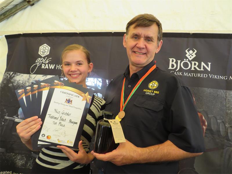 Two people pose with certificates and a bottled product in front of a banner that reads “Bjorn.”