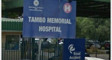 The signboard of Tambo Memorial Hospital displayed in bold white letters on a blue background.