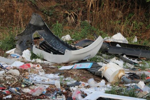Vehicle parts on the roadside with other waste material