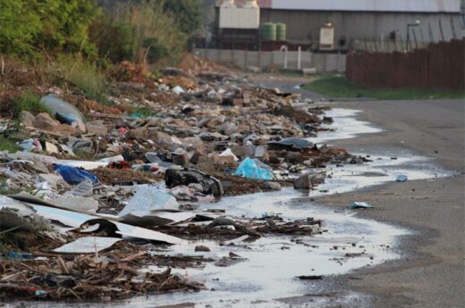 mountains of waste material and sewage leak flowing down a road