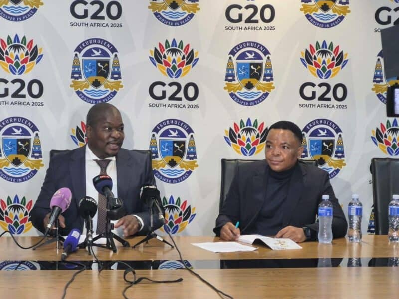 Ekurhuleni Mayor Doctor Xhakaza and Ekurhuleni city manager Kagiso Lerutla in the Mayor’s Parlour, with a white banner bearing the G20 and city of ekurhuleni logos in the background.