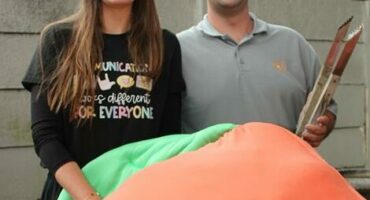 Woman with long dark hair with a man wearing a grey shirt.