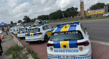 A group of police officers and a fleet of police vehicles parked next to each other on a public road.