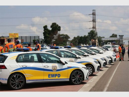 A group of police officers and a fleet of police vehicles parked next to each other on a public road.