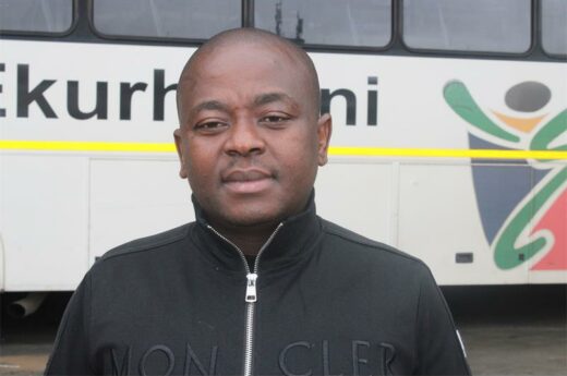 MMC of Roads and Transport Management, Andile Mngwevu, with a white municipal bus in the background.