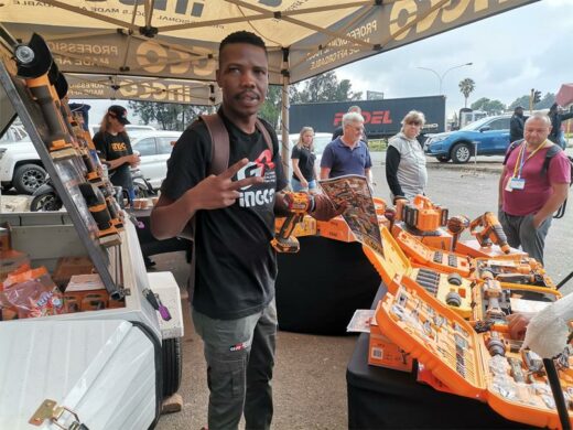 A young man posing for a photo with people several people in the background