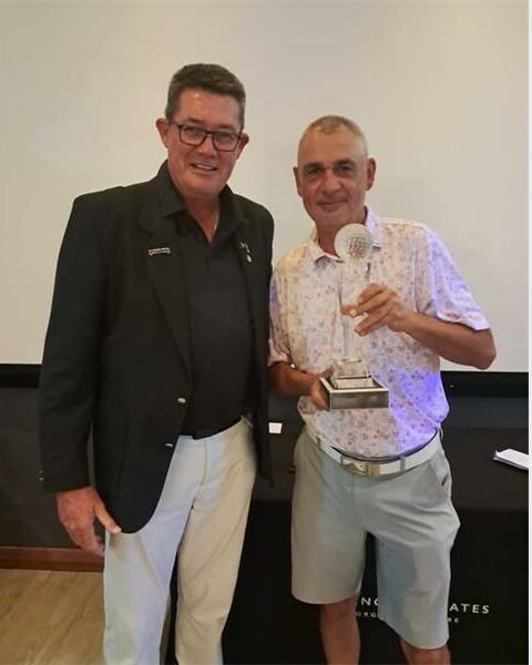 Ekurhuleni Golf Union president Jan Kruger in khaki pants and black top, with Kruger Jeremy Wright holding a trophy.
