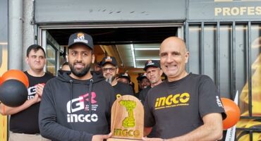 Witfield Hardware owner, Shabbeer Karolia and Ingco power tools South Africa managing director Angelo Angelos standing in front of a newly opened store, with balloons and a few people behind them.