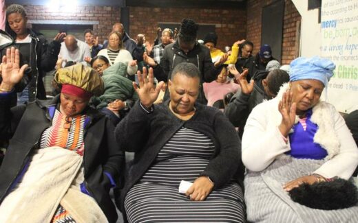 A group of people praying at a memorial service held in a church in Reiger Park. 