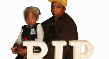 A coloured woman holding a baby at a memorial service in reiger park