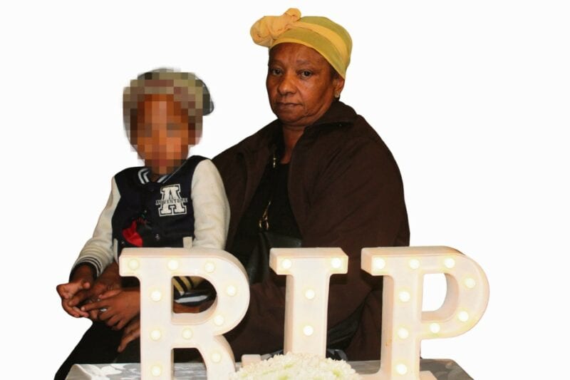A coloured woman holding a baby at a memorial service in reiger park