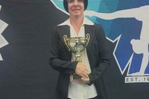 Coach of the year Colleen Jooste posing for a photo with a logo of the club in the background