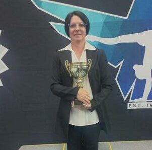 Coach of the year Colleen Jooste posing for a photo with a logo of the club in the background