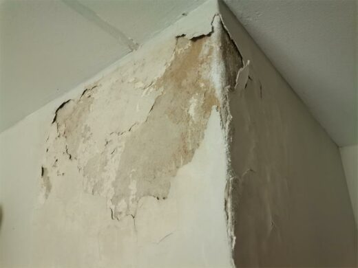 Cream white wall with cracks and blistering paint. Cream white wall with cracks and blistering paint.