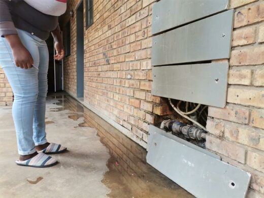 a woman standing next to a building with water leak a woman standing next to a building with water leak