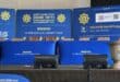 A police podium with banner and plaque featuring the official emblem, and badge of the SAPS.