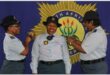 Police officers in uniform, with big SAPS banner