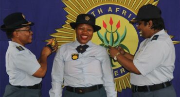 Police officers in uniform, with big SAPS banner
