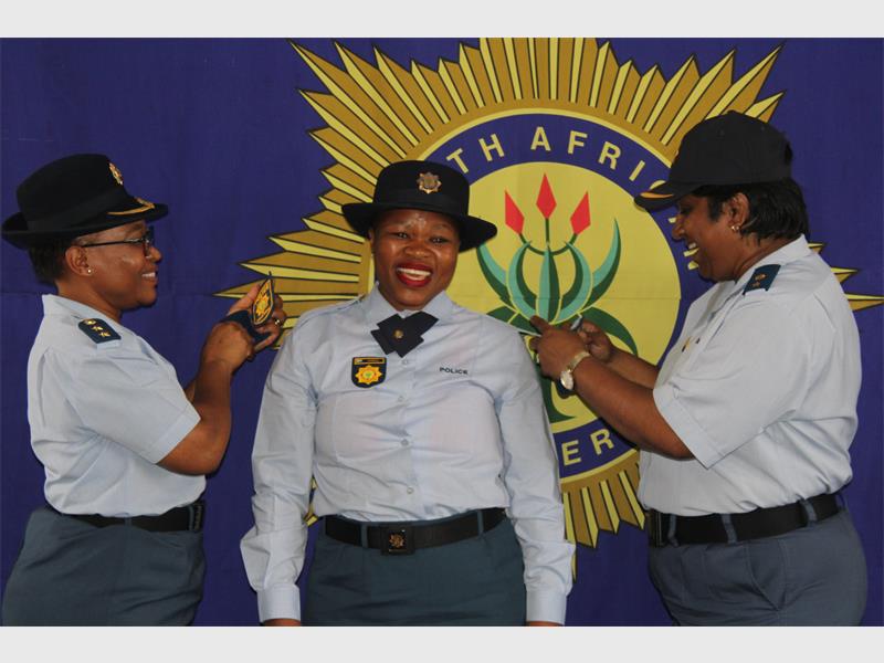 Police officers in uniform, with big SAPS banner