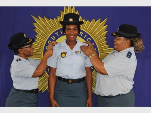 Police officers in uniform, with big SAPS banner