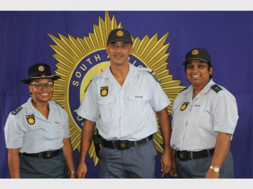 Police officers in uniform, with big SAPS banner