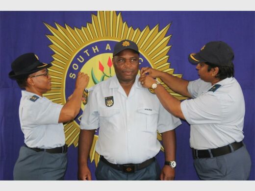 Police officers in uniform, with big SAPS banner