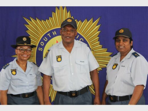 Police officers in uniform, with big SAPS banner