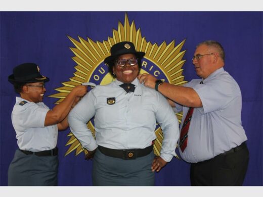 Police officers in uniform, with big SAPS banner