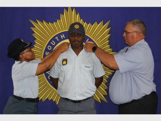 Police officers in uniform, with big SAPS banner