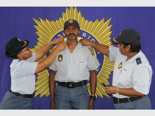 Police officers in uniform, with big SAPS banner