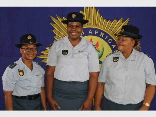 Police officers in uniform, with big SAPS banner