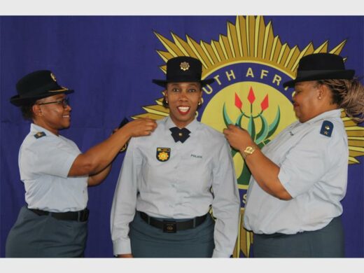 Police officers in uniform, with big SAPS banner