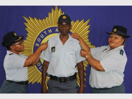 Police officers in uniform, with big SAPS banner