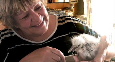 Woman smiling while holding a chick.