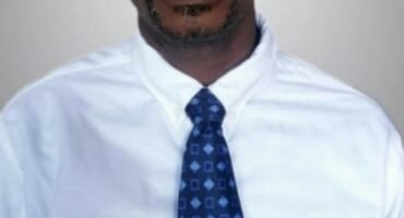 A Black man wearing a white shirt and a tie.