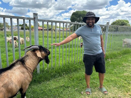 A black man standing next to a goat at Bokkie Park in Boksburg