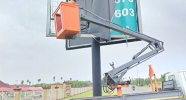 A black woman wearing reflective vest standing next to a billboard
