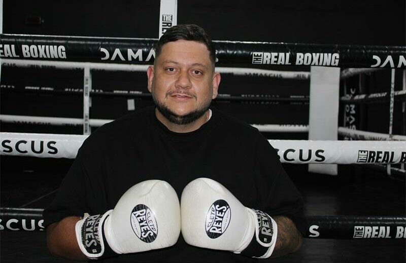 Man dressed in black t-shirt with boxing gloves.
