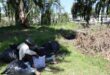 A group of men with their personal belongings sitting under a tree in a park