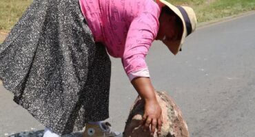 a woman rolling a rock onto the road
