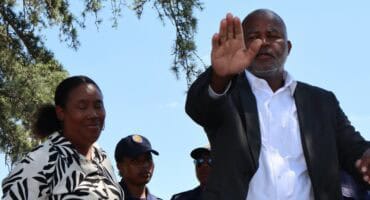 a black man and a woman addressing a crowd of pretesters