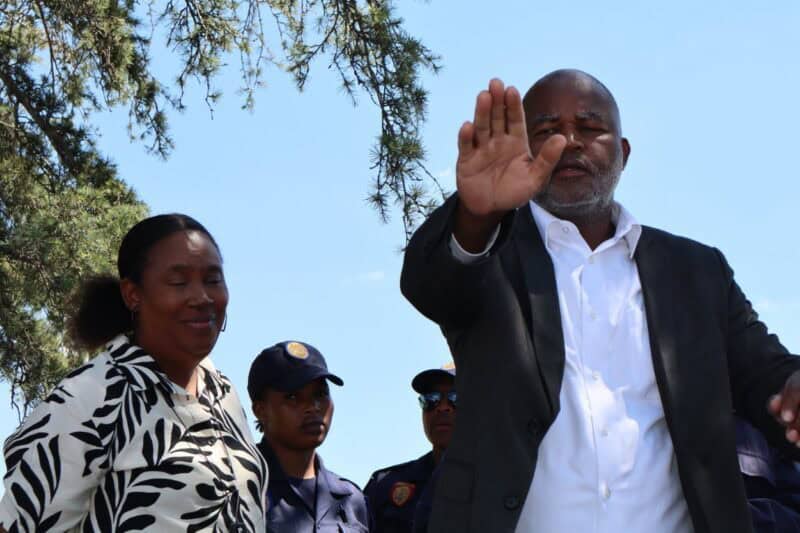 a black man and a woman addressing a crowd of pretesters