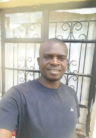 A Black male dressed in a navy T-shirt.